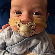 Arlo joined the competition — help win amazing prizes! baby, infant, pacifier, medical_tape, striped_clothing, bear_patch, onesie, cute, face, child, closeup, human, newborn, portrait, indoor, person, young_child, sleepwear, hand, soft_lighting