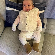 Lou participe au concours pour gagner de l'argent avec cette photo : baby, infant, smile, couch, pillow, white_vest, boots, leggings, mittens, indoor, happy, child, furniture, cozy, portrait, seated, home_interior, cute, warm_clothing, relaxed
