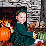 baby, bodypart, clothing, face, finger, fireplace, food, fruit, hand, head, indoors, leaf, person, photography, plant, portrait, produce, pumpkin, squash, vegetable