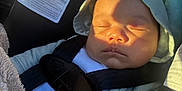 Elijah is registered to the contest to win money with this photo: baby, sleeping, car_seat, pacifier, sunlight, hood, safety_harness, blanket, infant, child, clothing, warning_label, closeup, indoors, seatbelt, nap, cute, peaceful, resting, toddler