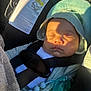 baby, sleeping, car_seat, pacifier, sunlight, hood, safety_harness, blanket, infant, child, clothing, warning_label, closeup, indoors, seatbelt, nap, cute, peaceful, resting, toddler