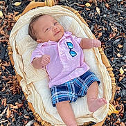 Elijah is registered to the contest to win money with this photo: baby, basket, plaid_shorts, pink_shirt, sunglasses_patch, autumn_leaves, mulch, outdoor, infant, smiling, clothing, fabric, woven, foot, hand, face, nature, seasonal, relaxed, portrait