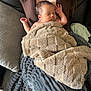 baby, sleeping, blanket, couch, person, adult, brown_clothing, cozy, indoor, comfort, soft_texture, relaxation, head, arm, pillow, fabric, home, rest, infant, peaceful