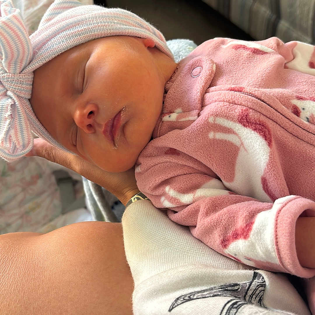 Gwendolyn is registered to the contest to win money with this photo: arm, baby, bow, closeup, couch, cozy, fabric, hand, hat, indoor, infant, newborn, peaceful, person, pink_clothing, portrait, relaxation, resting, skin, sleeping