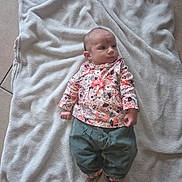 Wayna a rejoint le concours — aidez-le/la à gagner de superbes lots ! baby, blanket, floor, tile, clothing, pants, socks, person, infant, cute, indoor, soft, fabric, pattern, floral, bow, small, lying_down, footwear, young_child