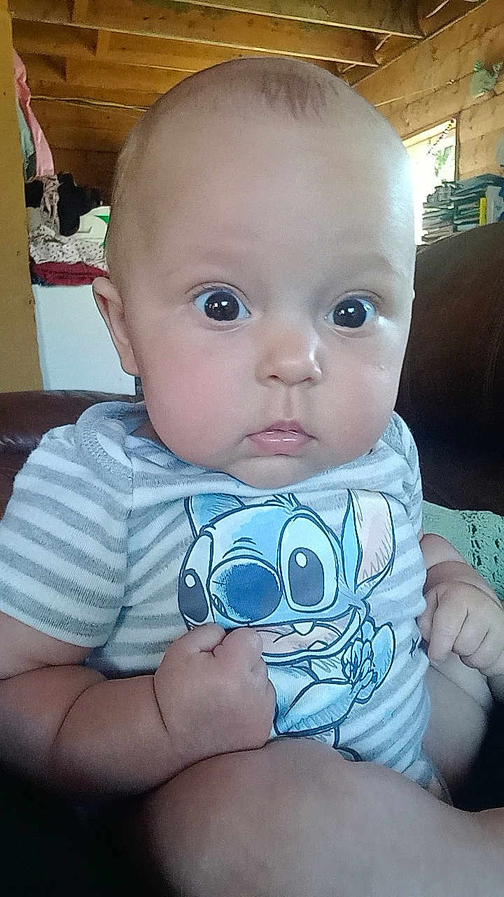 Saranae joined the competition — help win amazing prizes! baby, infant, child, person, face, eyes, hand, fist, clothing, striped_shirt, cartoon_character, indoor, wooden_wall, couch, furniture, curious_expression, closeup, portrait, cute, homedecor