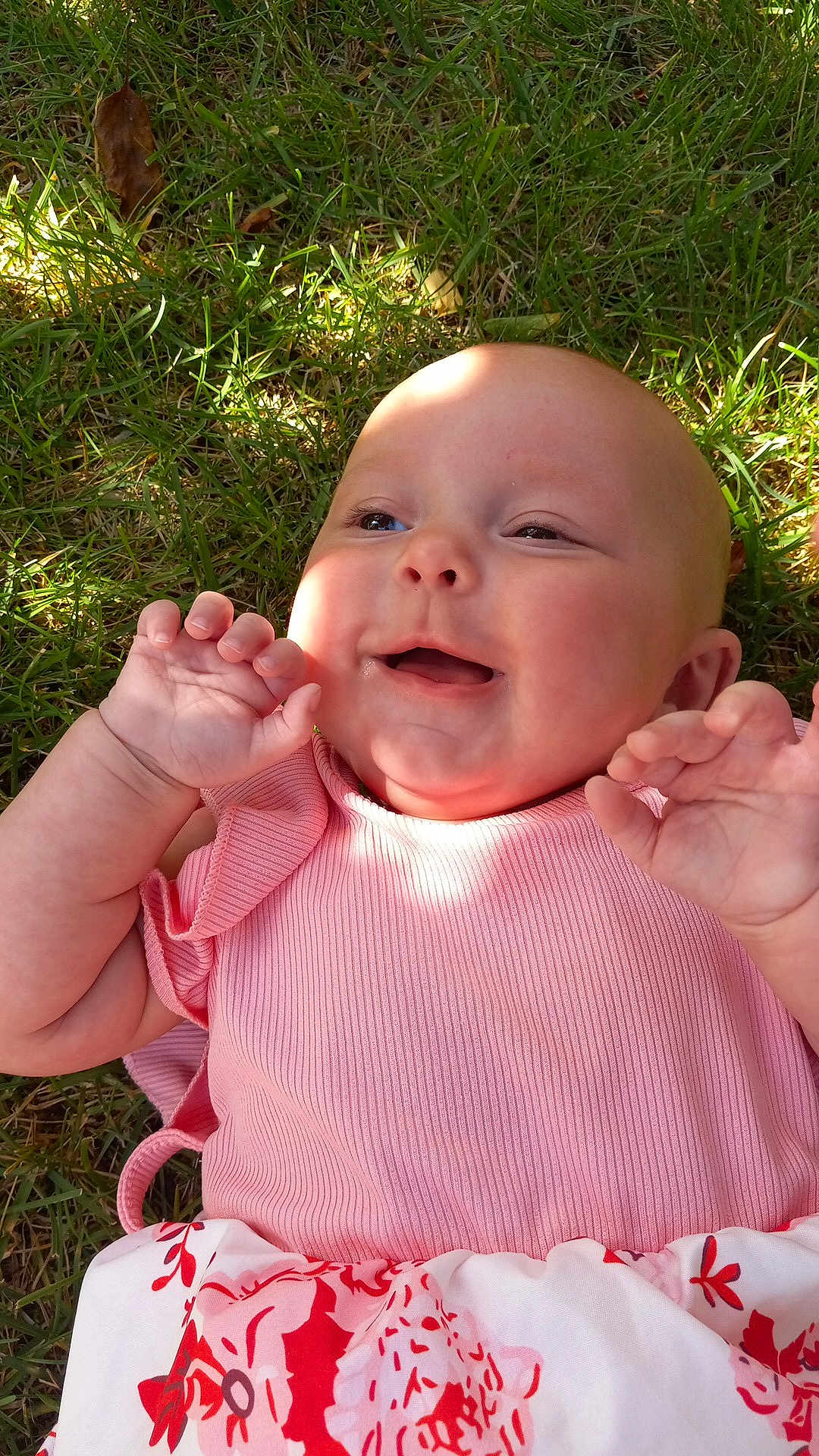 Saranae is registered to the contest to win money with this photo: baby, child, cute, face, floral_pattern, grass, hands, happy, head, infant, lying_down, nature, outdoor, pink_dress, playful, skin, smiling, sunlight, toddler, young_child