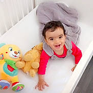 Aymen participe au concours pour gagner de l'argent avec cette photo : baby, crib, stuffed_toy, blanket, crawling, smiling, child, indoor, white, soft_toys, happy, cute, infant, flooring, bedroom, playful, clothing, toddler, person, face