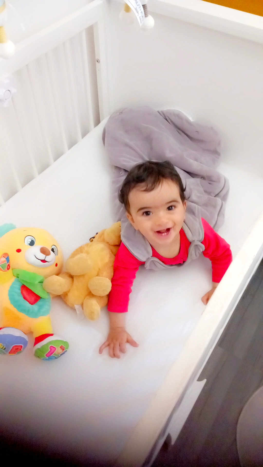 Aymen participe au concours pour gagner de l'argent avec cette photo : baby, crib, stuffed_toy, blanket, crawling, smiling, child, indoor, white, soft_toys, happy, cute, infant, flooring, bedroom, playful, clothing, toddler, person, face