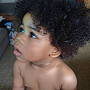 Kaleb is registered to the contest to win money with this photo: toddler, child, curly_hair, indoor, portrait, baby, skin, expression, eyes, face, hair, person, young_child, couch, living_room, curiosity, close_up, natural_light, cute, bare_chest