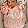 baby, infant, smile, knitted_sweater, peach_color, face, eyes, arms, bedding, blanket, floral_pattern, animal_pattern, cute, newborn, portrait, soft_lighting, indoors, cozy, clothing, person