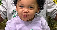 Kaylani joined the competition — help win amazing prizes! toddler, child, curly_hair, purple_shirt, lemon_patch, smile, face, person, sitting, adult, white_shirt, green_background, indoor, cute, portrait, happy, playful, young_child, casual_clothing, closeup