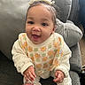 Kaylani joined the competition — help win amazing prizes! baby, child, smiling, happy, couch, indoor, hand, clothing, bib, face, person, sitting, cute, infant, cozy, furniture, headwear, expression, skin, young