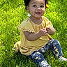 toddler, child, grass, outdoor, yellow_top, floral_leggings, curly_hair, flower, dandelion, smiling, sunlight, nature, happy, cute, sitting, greenery, baby, casual_clothing, daylight, portrait