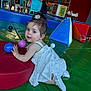 toddler, child, indoor, play_area, colorful, ball, red_cushion, blue_cushion, white_dress, playground, person, floor_mat, toy, young_child, curly_hair, play, happy, cute, baby_shoes, activity
