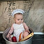 baby, child, chef_hat, apron, pot, kitchen, vegetable, carrot, red_pepper, wooden_spatula, stove, cooking, cute, indoor, person, food, playful, cooking_pot, infant, adorable