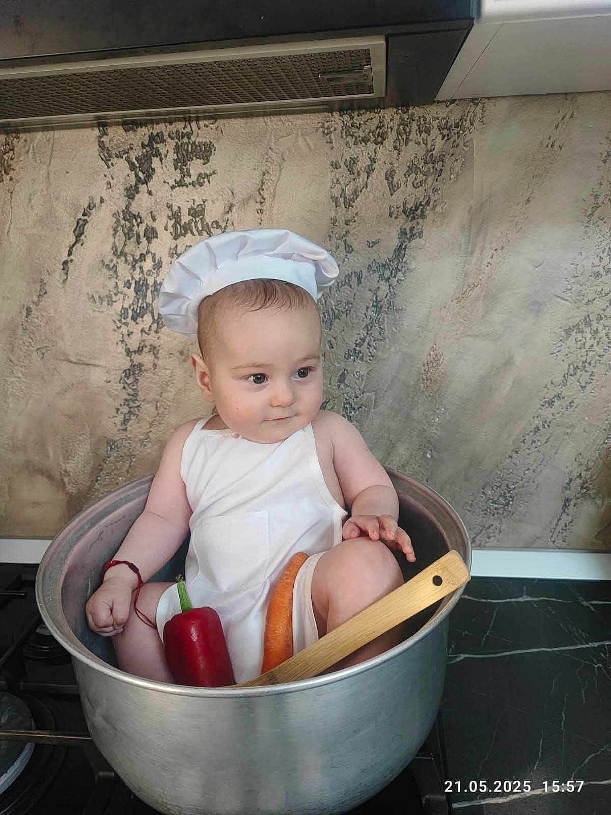 Luca Nicolae joined the competition — help win amazing prizes! baby, child, chef_hat, apron, pot, kitchen, vegetable, carrot, red_pepper, wooden_spatula, stove, cooking, cute, indoor, person, food, playful, cooking_pot, infant, adorable