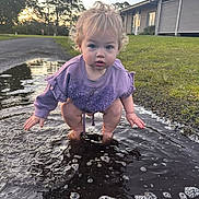 Ivy joined the competition — help win amazing prizes! toddler, child, puddle, water, outdoor, grass, curly_hair, purple_sweater, squatting, playful, sunset, pathway, bubbles, building, nature, reflection, person, young_child, casual_clothing, daylight