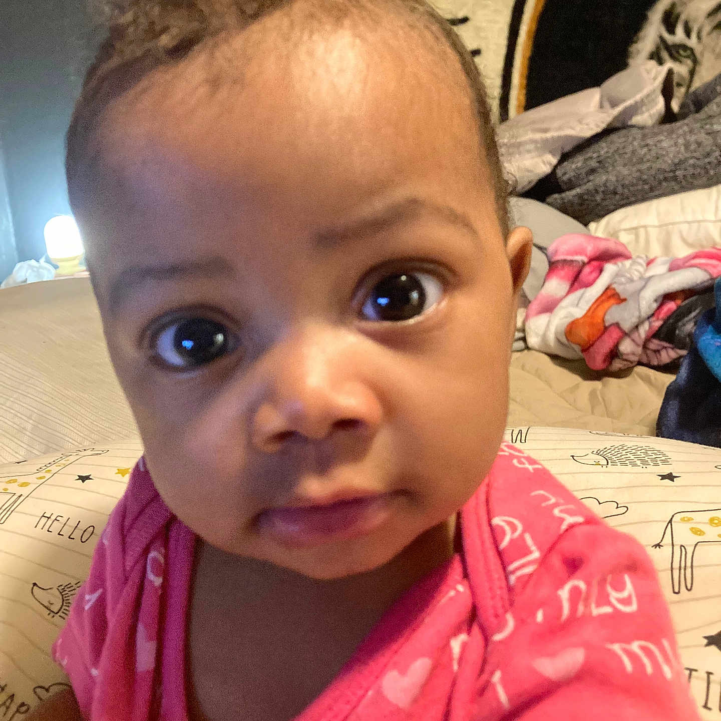 Amylah joined the competition — help win amazing prizes! baby, blanket, child, close_up, cozy, curious, cute, expression, eyes, face, head, indoor, infant, lamp, person, pillow, pink_clothing, portrait, soft_lighting, young_child