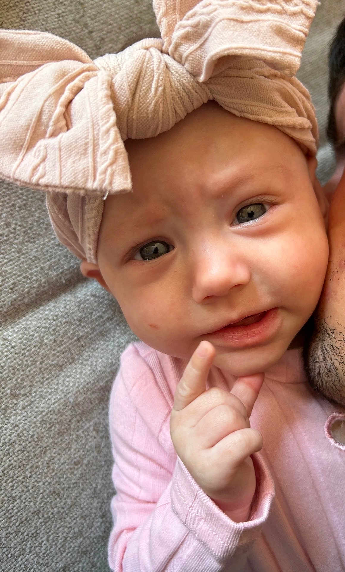 Alma participe au concours pour gagner de l'argent avec cette photo : baby, infant, pink_bow, headwear, hand, face, eyes, expression, person, skin, clothing, fabric, texture, adult, closeup, portrait, cute, indoor, curious, pointing
