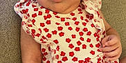 Alma participe au concours pour gagner de l'argent avec cette photo : baby, infant, child, dress, red_flowers, white_clothing, couch, beige, furniture, portrait, face, eyes, hand, skin, sitting, indoor, young_child, cute, looking_at_camera, expression