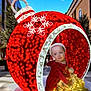 child, christmas, ornament, holiday, decoration, lights, red, outdoor, urban, building, tree, sky, festive, baby, string_lights, holiday_season, celebration, winter, festivity, portrait