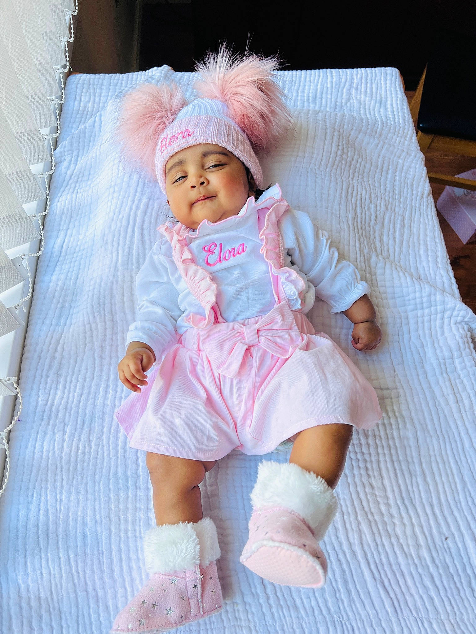 Elora joined the competition — help win amazing prizes! baby, baby_toddler_clothing, child, doll, embellishment, face, fashion_design, headwear, human_leg, lap, linens, outerwear, pattern, peach, person, pink, sitting, skin, sleeve, sock