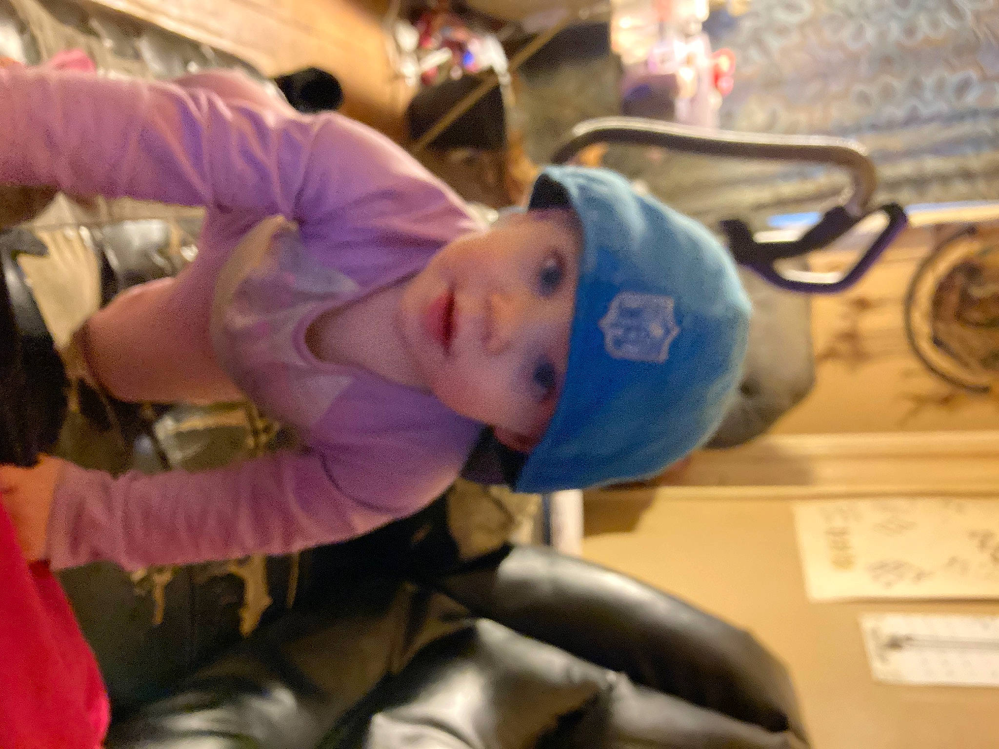 Isabella is registered to the contest to win money with this photo: auto_part, baby, child, electric_blue, fun, glove, headwear, leisure, person, personal_protective_equipment, room, sitting, sports_gear, toddler