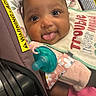 Kadence is registered to the contest to win money with this photo: baby, infant, tongue_out, car_seat, pacifier, bib, pink_clothing, face, cute, child, close_up, smiling, seatbelt, warning_label, expression, adorable, portrait, indoor, young_child, baby_accessory