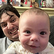 Ethan is registered to the contest to win money with this photo: baby, man, smile, face, hand, pajamas, indoor, holiday_decorations, snowman, santa_figure, christmas, portrait, closeup, playful, funny_face, person, couch, photography, family, celebration