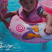 Royalty is registered to the contest to win money with this photo: cartoon, child, family, floatie, front_facing, inflatable_ring, outdoor, pink, pool, portrait, recreation, second_child, serious_expression, summer, swimming_pool, swimsuit, toddler, water, water_play, wet_hair