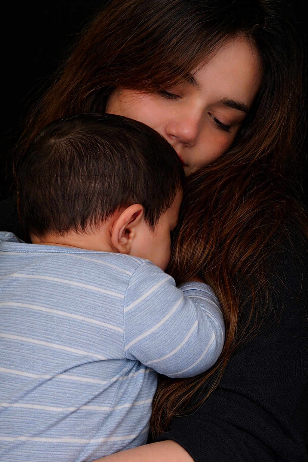 Hamad joined the competition — help win amazing prizes! arm, baby, close_up, comfort, cuddling, dark_background, face, hair, hug, indoor, infant, mother, onesie, parent_child, portrait, skin, sleeping, striped_onesie, tender_moment, woman