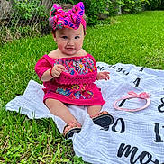 Alejandra is registered to the contest to win money with this photo: baby, child, grass, blanket, headband, pink_dress, outdoor, greenery, fence, footwear, sitting, portrait, cute, smile, summer, nature, colorful_clothing, young_child, happy, headwear