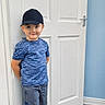 Corey joined the competition — help win amazing prizes! blue_shirt, boy, cap, casual_clothing, child, feet, floor, happy, indoor, light, person, portrait, room, shorts, smile, sneakers, socks, standing, wall, white_door