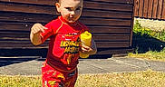 Corey joined the competition — help win amazing prizes! barefoot, boy, casual, child, daylight, fence, grass, lightning_mcqueen, outdoor, playtime, portrait, red_clothing, shadow, shorts, sippy_cup, smiling, summer, sunny, toddler, wooden_shed