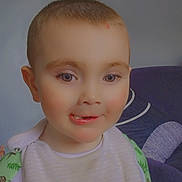 Corey is registered to the contest to win money with this photo: toddler, child, smiling, bib, teddy_bears, face, indoor, couch, pillow, mirror, wall, butterfly, short_hair, green_clothing, white_bib, person, portrait, cute, happy, seated