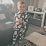 Corey joined the competition — help win amazing prizes! child, toddler, pajamas, ghost_pattern, smiling, indoor, living_room, rug, snack, curtains, sofa, picture_frame, carpet, socks, wooden_floor, toy, shelf, cozy, daylight, home