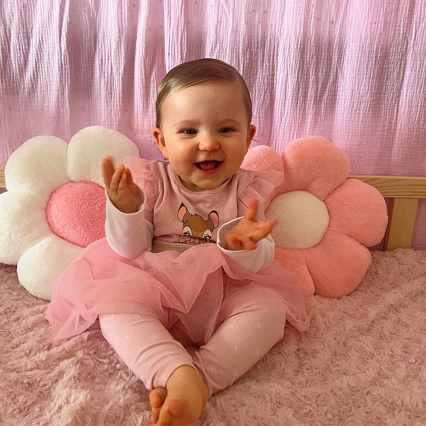 Lilya participe au concours pour gagner de l'argent avec cette photo : baby, child, pink, tutu, smiling, clapping, plush_pillow, flower_pillow, soft_blanket, indoors, cute, happy, person, sitting, infant, head, face, legs, barefoot, background