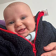 Dion a rejoint le concours — aidez-le/la à gagner de superbes lots ! baby, smiling, face, hand, jacket, zipper, red, black, cozy, clothing, portrait, indoor, child, person, happy, cute, skin, head, photography, nail_polish