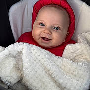 Dion Lleshi a rejoint le concours — aidez-le/la à gagner de superbes lots ! baby, smiling, red_hood, blanket, cozy, face, infant, happy, portrait, child, cute, warm, clothing, blanket_texture, snug, closeup, person, baby_face, outdoor_gear, bundle