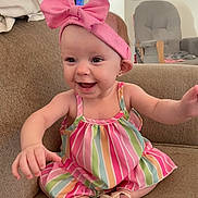 Winter is registered to the contest to win money with this photo: baby, child, smiling, happy, pink_bow, headband, striped_dress, sitting, couch, indoor, shoes, cute, infant, portrait, person, furniture, home, room, joy, expression