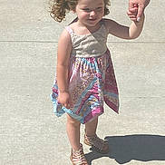 Olivia is registered to the contest to win money with this photo: child, girl, curly_hair, pigtails, dress, sandals, sidewalk, shadow, hand_holding, sunny, outdoor, person, walking, summer, casual_clothing, young_child, skin, footwear, human, daylight