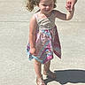 child, girl, curly_hair, pigtails, dress, sandals, sidewalk, shadow, hand_holding, sunny, outdoor, person, walking, summer, casual_clothing, young_child, skin, footwear, human, daylight