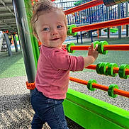 Sophia is registered to the contest to win money with this photo: toddler, child, playground, abacus, smile, happy, outdoor, colorful, toy, clothing, pants, shirt, hand, hair, face, person, play, daylight, fun, development