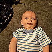 Kaspian is registered to the contest to win money with this photo: arm, baby, blanket, bow_tie, child, clothing, curious, cute, expression, eyes, fabric, face, hand, indoor, infant, laying_down, person, skin, striped_shirt, texture