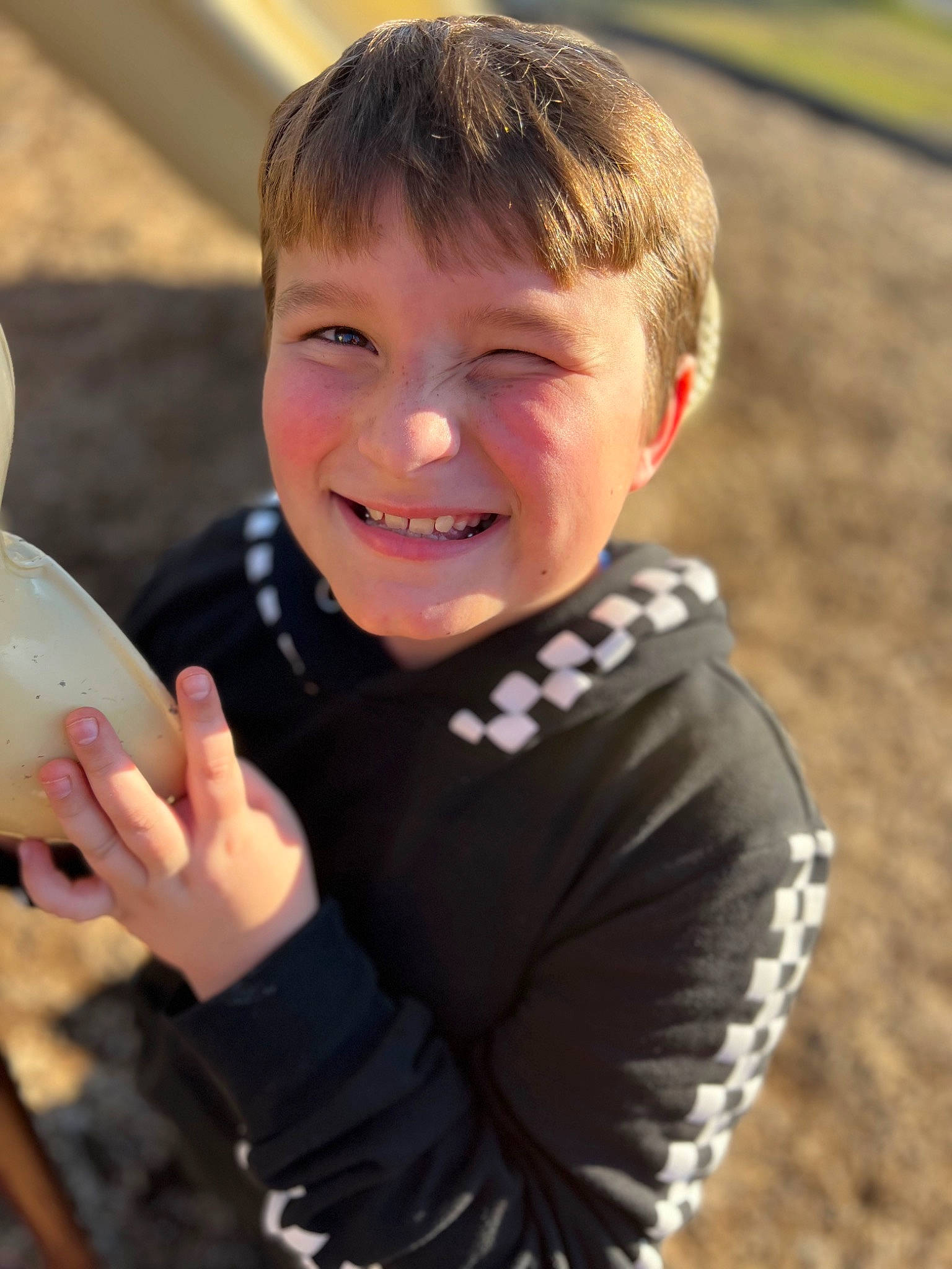 Maddox is registered to the contest to win money with this photo: arm, child, flash_photography, fun, gesture, grass, happy, joy, laugh, leisure, people_in_nature, person, personal_protective_equipment, play, recreation, sitting, smile, soil, t_shirt, thumb