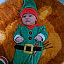 Tao participe au concours pour gagner de l'argent avec cette photo : baby, child, colorful, costume, cute, elf_costume, festive, floor, green_clothing, headwear, holiday, indoors, infant, lying_down, orange_rug, person, portrait, red_hat, small_hands, soft_texture