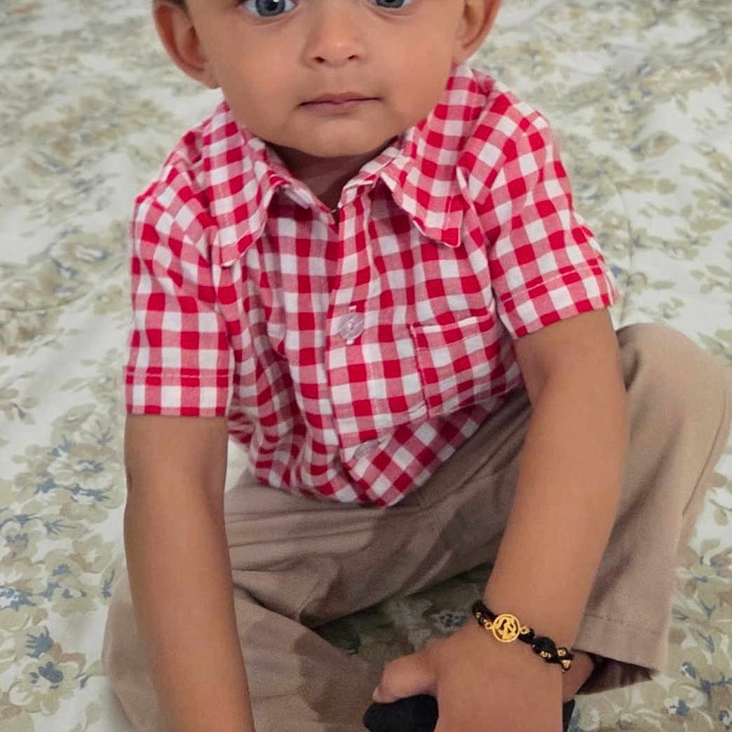 Agastya joined the competition — help win amazing prizes! toddler, child, boy, blue_eyes, curly_hair, red_checkered_shirt, beige_pants, bracelet, shoe, sitting, indoor, carpet, portrait, cute, young_child, expression, hands, footwear, floor, home