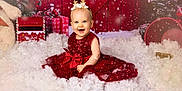 Luna a rejoint le concours — aidez-le/la à gagner de superbes lots ! baby, celebration, child, christmas, cute, decorations, festive, gift, happy, headband, holiday, indoor, portrait, present, red_dress, sitting, smiling, snow, sparkle, winter