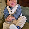 Zixton is registered to the contest to win money with this photo: baby, child, smiling, sitting, vest, pants, shoe, tongue_out, happy, indoor, furniture, chair, patterned, cute, portrait, infant, hands_clasped, person, footwear, casual